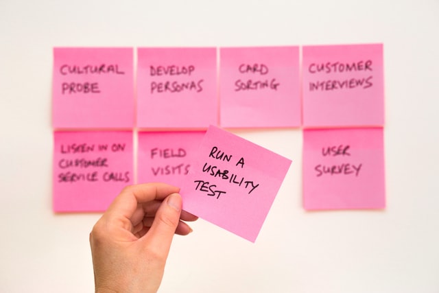 a person holding a sticky note that reads run a usability test