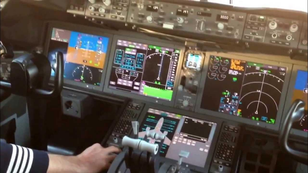 The image showcases the advanced HMI of a Boeing 787 Dreamliner cockpit, featuring high-resolution multifunction displays that provide real-time flight data, navigation, and aircraft systems monitoring for enhanced pilot control and situational awareness.